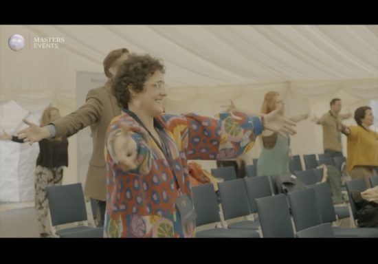 Participants engage joyfully in an activity with arms outstretched in a tent.