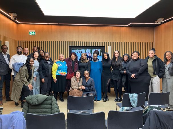 Group photo of diverse individuals posing together in a modern indoor space.