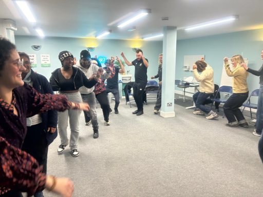 A group of people dancing and engaging in a lively activity in a community hall.